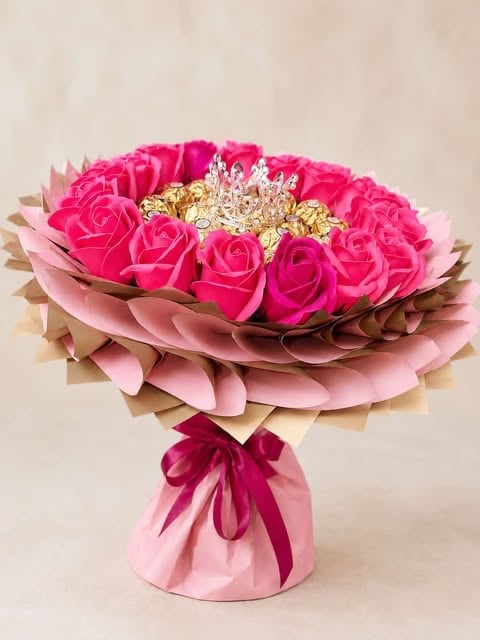 Luxurious bouquet of hot pink roses with golden decorative elements, wrapped in layered pink and beige paper with a ribbon bow
