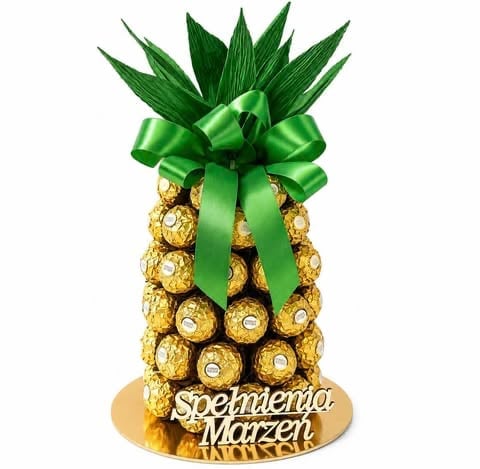 Decorative pineapple made of gold foil-wrapped chocolates with green leaves and ribbon bow on a base
